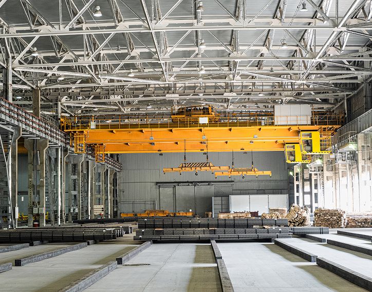 Industrial facility interior with overhead crane system and steel material handling area for automation and drive system integration